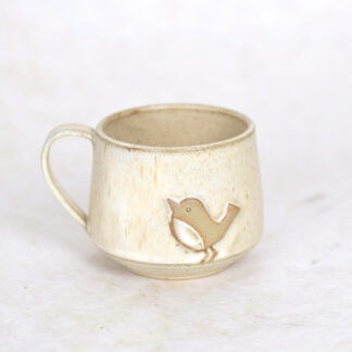 beige keamieken theekop met vogelmotief o witte achtergrond