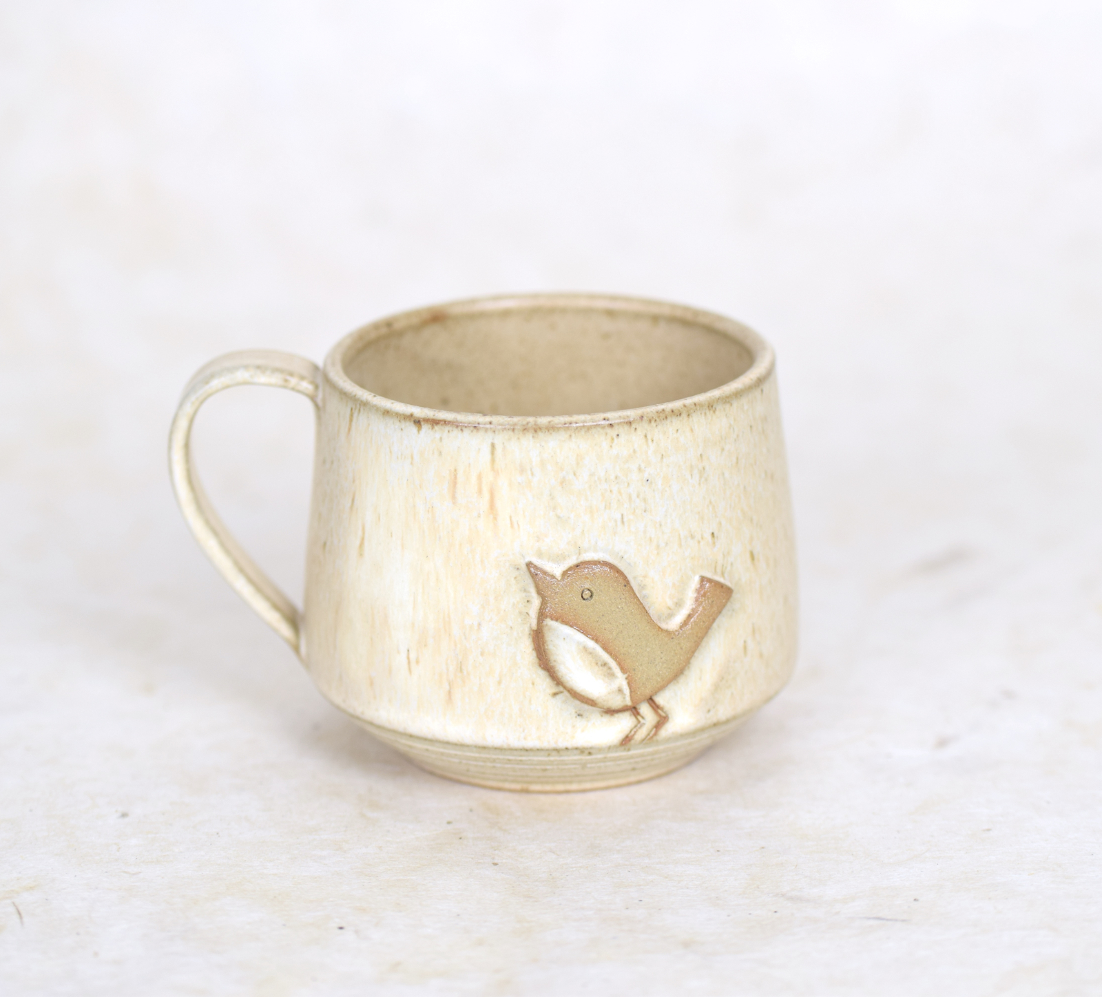 beige keamieken theekop met vogelmotief o witte achtergrond