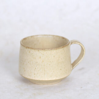 beige keramieken theekop met oor op witte achtergrond
