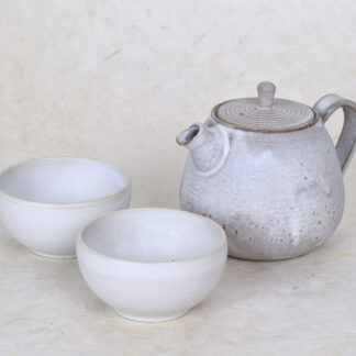 een wit beige theekan met twee witte theekopjes